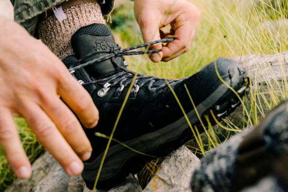 Close-up of a man in black hiking boots tying his shoes